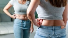 A woman looking at belly fat in the mirror