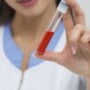 A woman holding a test tube of blood.