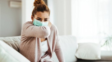 A woman wearing a mask and coughing